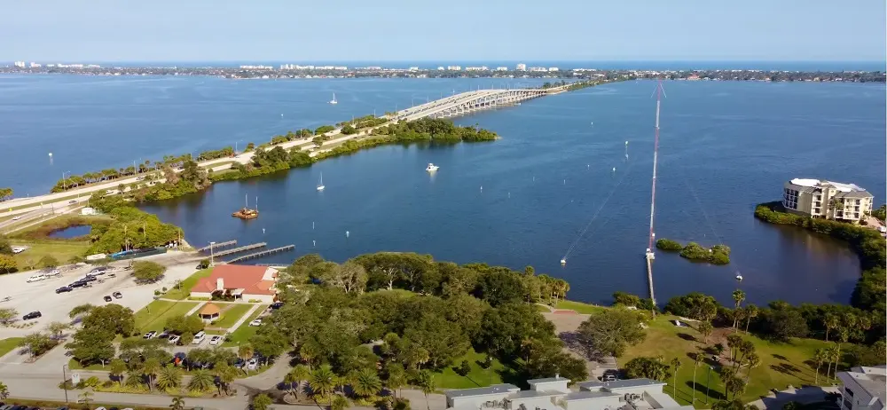 Melbourne displays a causeway stretching across calm blue waters flanked by verdant parkland, captured by Space Coast Dumpster Rental