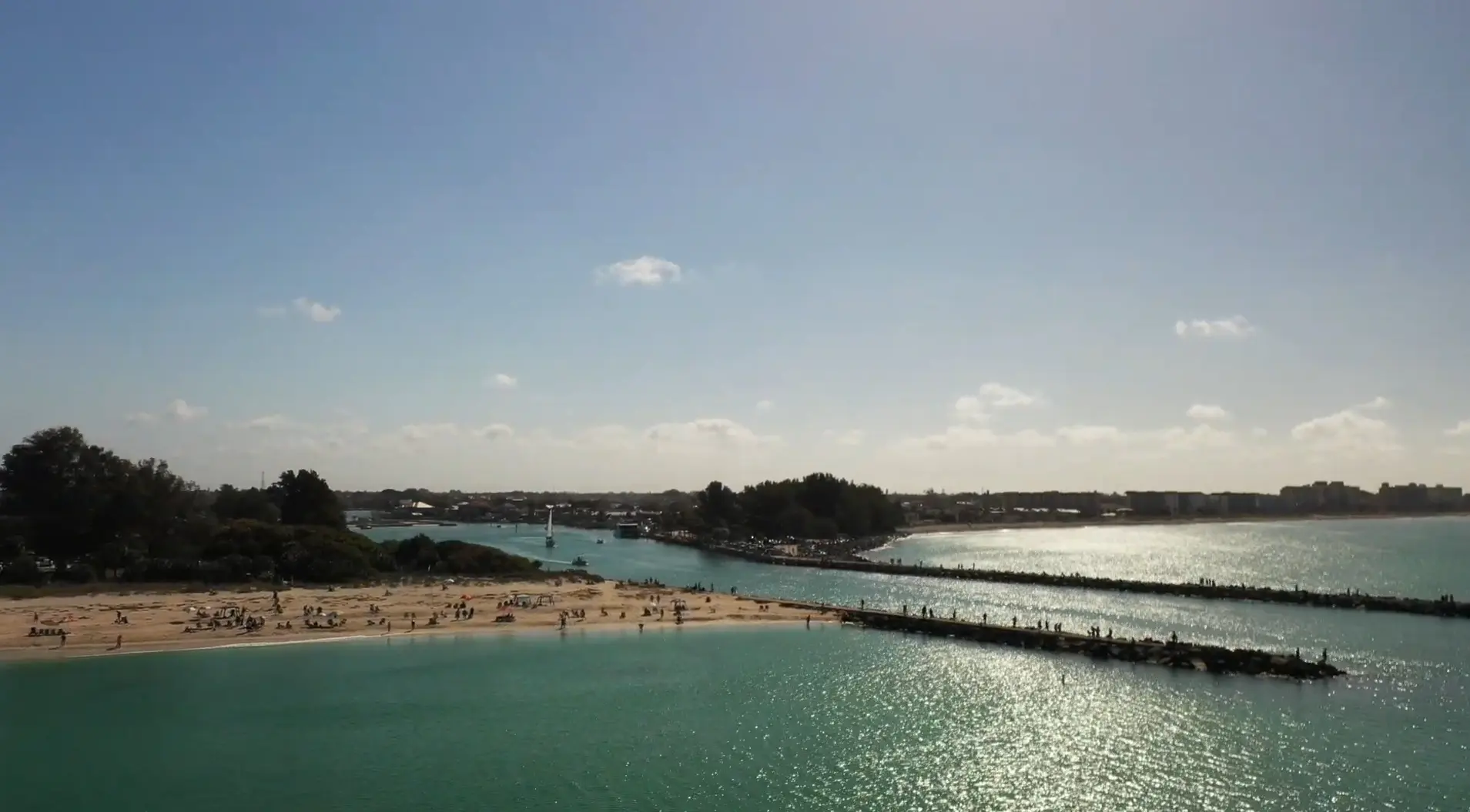 Merritt Island captures a sunlit inlet where sandy shores and seawalls meet tranquil turquoise waters, photographed by Space Coast Dumpster Rental
