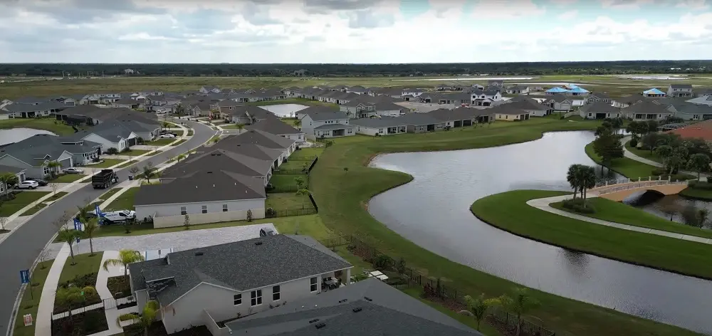 Palm Bay rooftops, parklands, community amenities with roll-off truck with dumpster in the background seen in drone view by Space Coast Dumpster Rental
