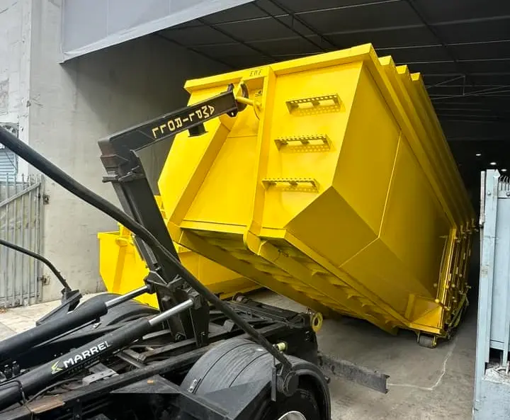 Space Coast Dumpster Rental unloads a roll-off dumpster with a hook-lift system at a service facility