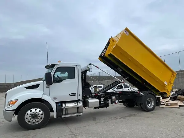 Space Coast Dumpster Rental roll off truck unloading a yellow container at a job site