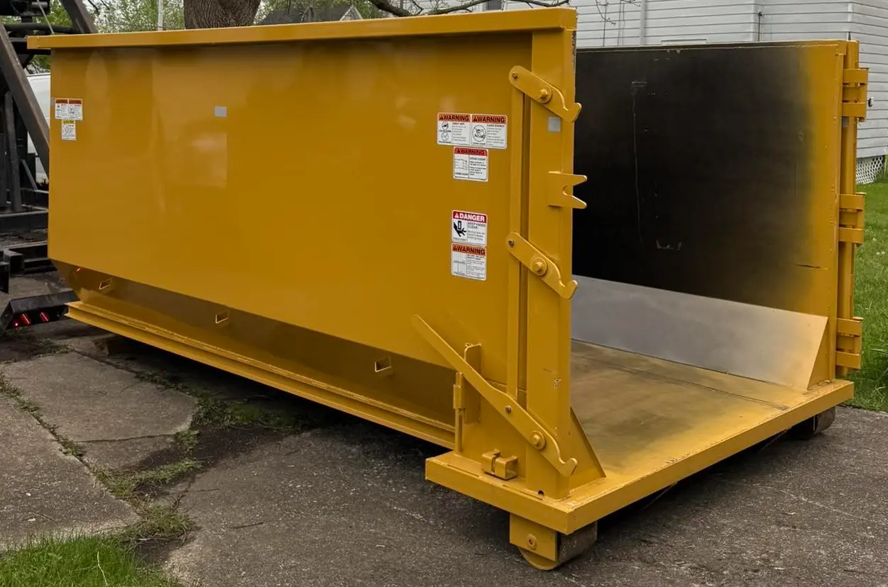 Space Coast Dumpster Rental yellow dumpster set down at home site with open rear gate ready for use