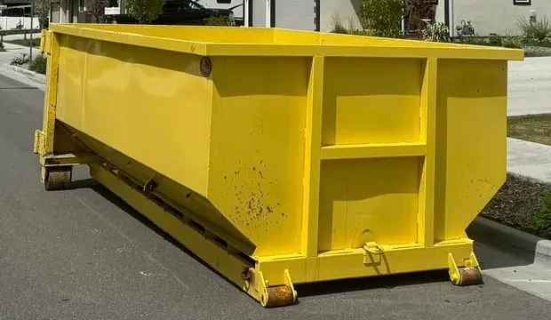 Space Coast Dumpster Rental places a yellow roll-off dumpster along a residential street in front of homes