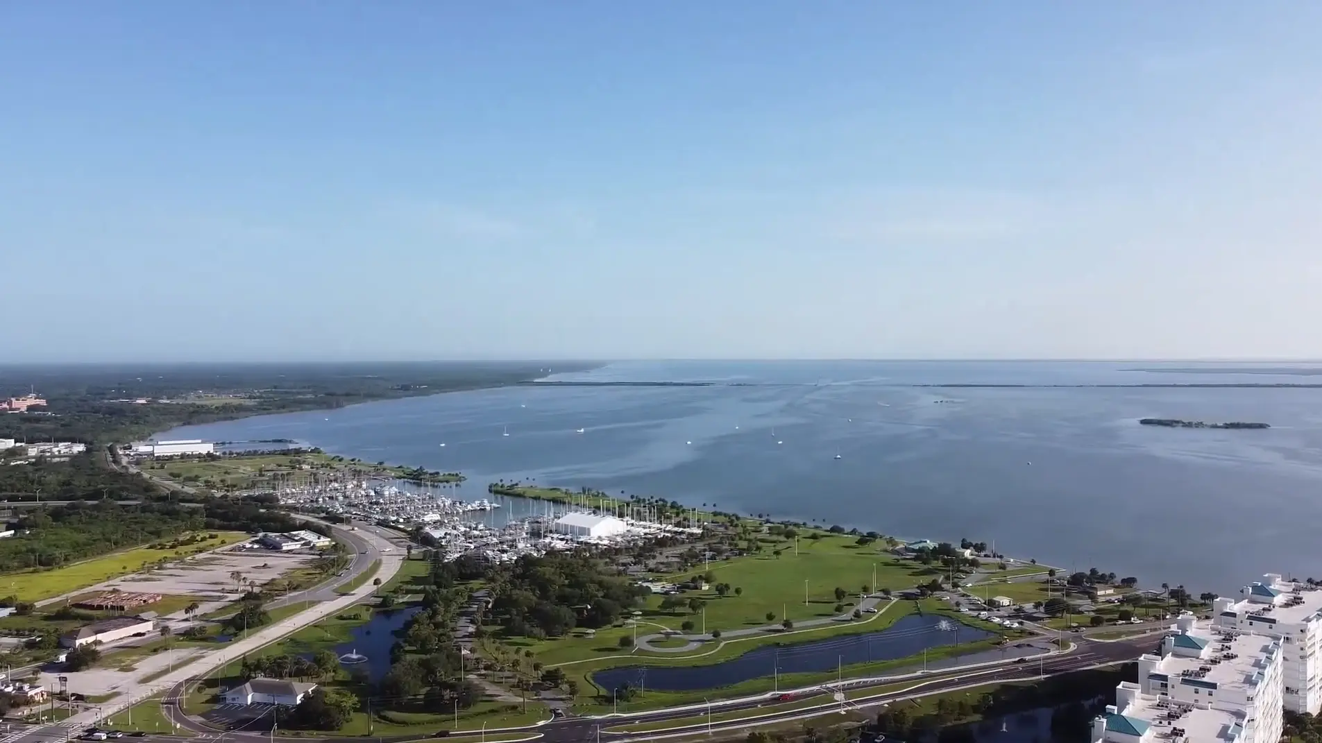 Titusville shows a coastal marina curving along the shoreline as Space Coast Dumpster Rental captures a panoramic aerial view
